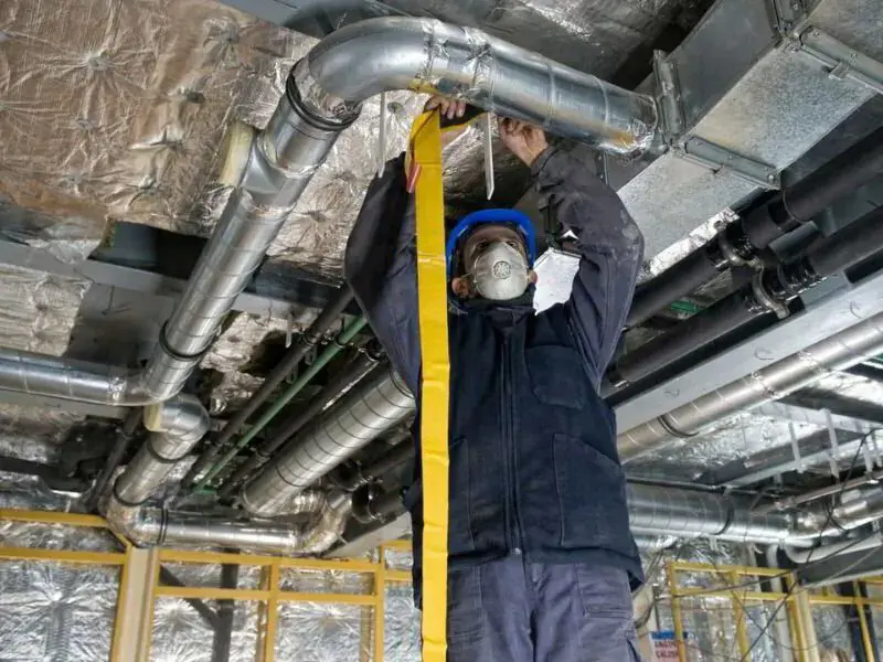 HVAC technician sealing a duct with tape